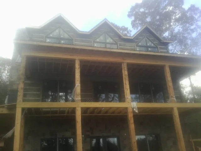 Dormers and porch framing on a large log home under construction — Roof Coating work by our crew in Dixon