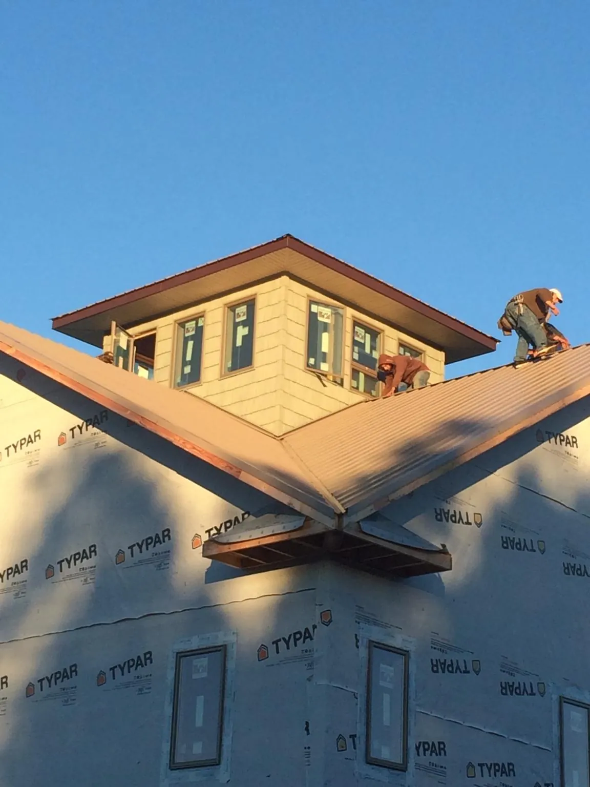 Roofers working around a rooftop cupola on a new metal roof at sunset — Roof Waterproofing in Dixon by Roofing Brothers